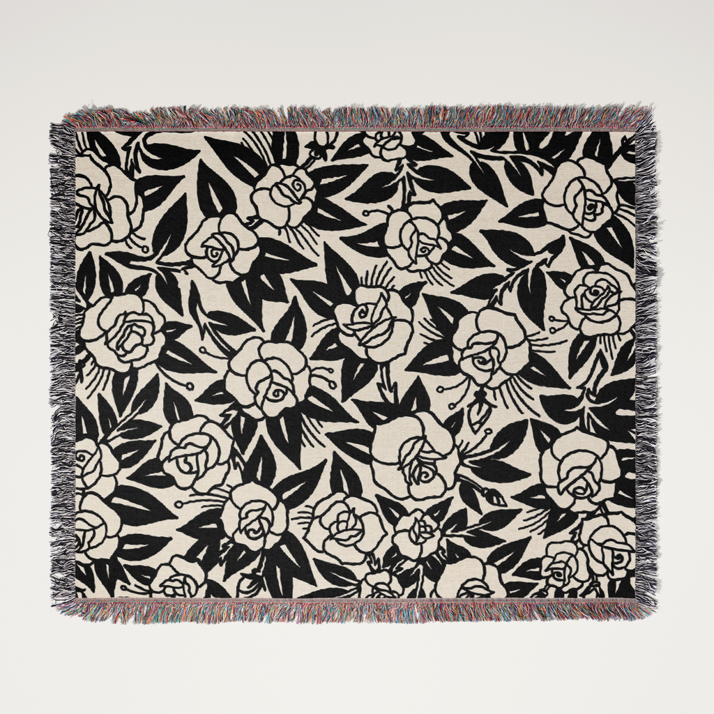 Floral patterned throw blanket with black roses on a beige background