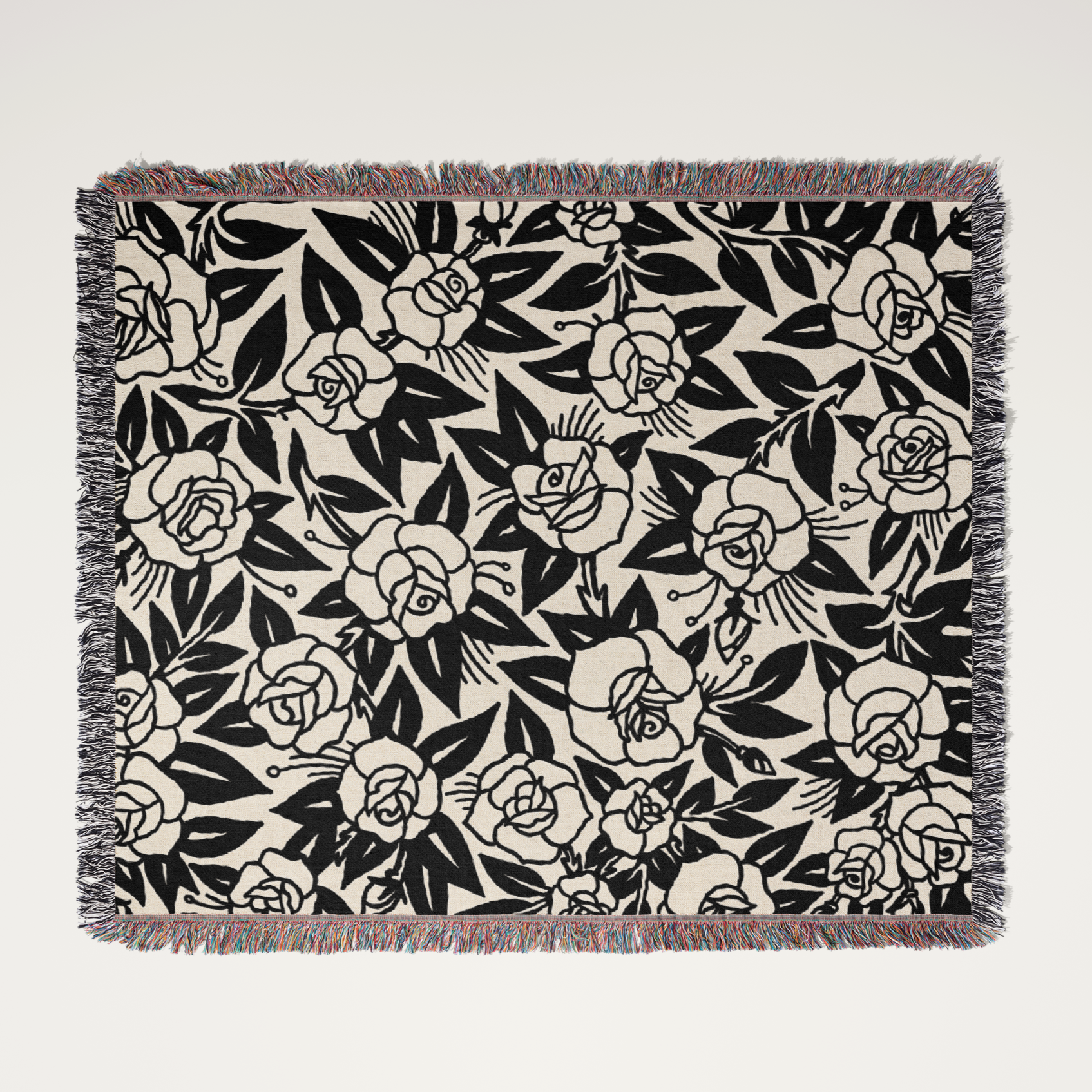 Floral patterned throw blanket with black roses on a beige background